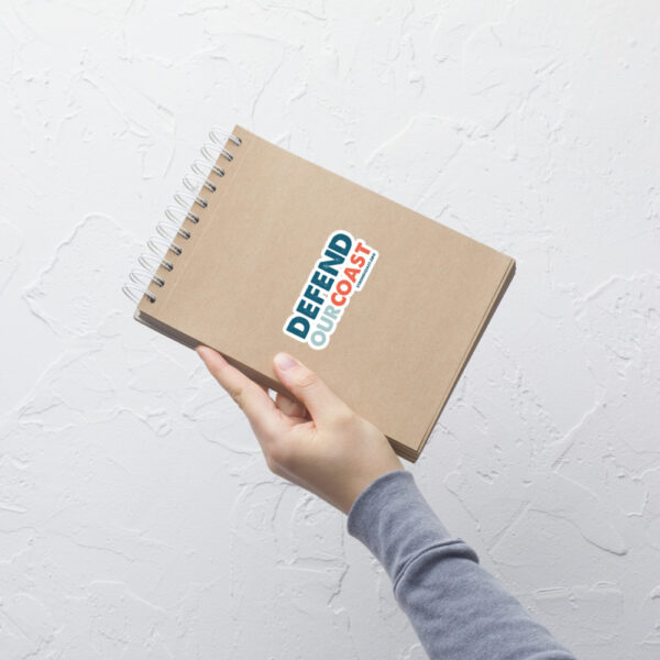 A notebook with a "Defend our Coast" sticker