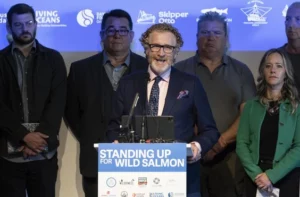 A speaker at the podium with the words "Standing Up for Wild Salmon"